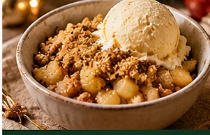 Appelcrumble met amandel en vanille-ijs geserveerd op een feestelijke kersttafel